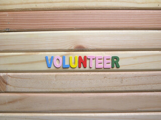 Word Volunteer on wood background