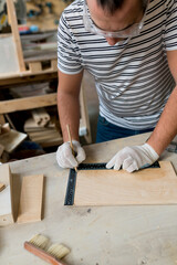 Close up of Man joiner measuring  wooden board with ruler with scale in workshop. Carpentery work on the production and renovation of wooden furniture. Small Business Concept