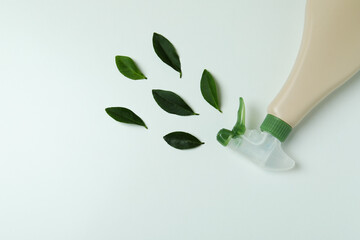 Blank detergent spray bottle and leaves on white background