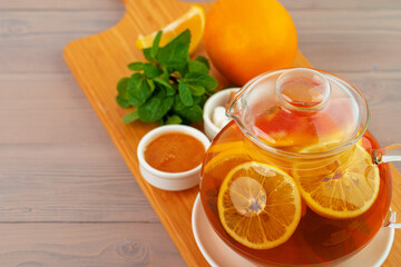 Glass teapot with black tea and pieces of citrus