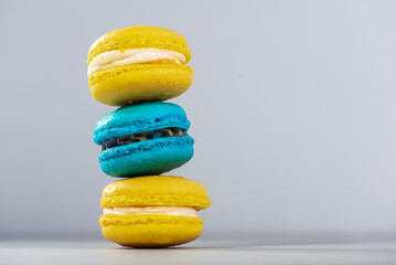 Sweet, tasty and colorful - blue and yellow french macarons on a light background, one on top of the other, a pyramid. The dessert is sweet. Selective focus. Sweet concept