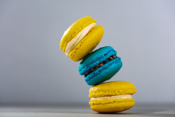 Sweet, tasty and colorful - blue and yellow french macarons on a light background, one on top of the other, a pyramid. The dessert is sweet. Selective focus. Sweet concept