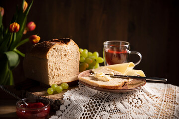 Frühstück ist fertig! Brot ist geschnitten, mit Butter geschmiert, Glas Tee , Weintrauben, Tulpen...