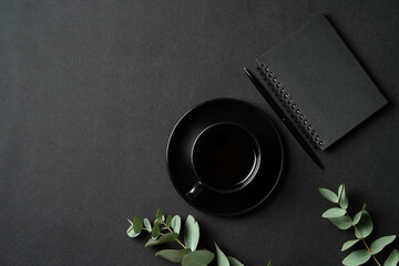 Luxury style office desk table with cup of coffee, paper notebook, pen, eucalyptus branch on...