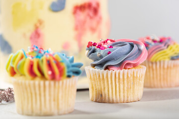 Matte cupcakes in yellow, blue and pink on a light surface. Selective focus. Birthday or Christmas cake, holiday.