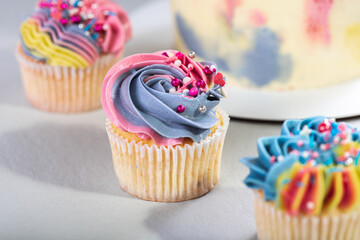 Matte cupcakes in yellow, blue and pink on a light surface. Selective focus. Birthday or Christmas cake, holiday.