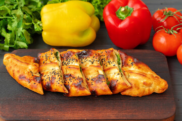 Stuffed bread, turkish pie with herbs on wooden board