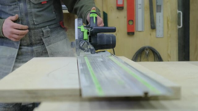Close up. Carpenter at workshop polishes wooden board with a electric orbital sander. Woodwork and furniture making concept.