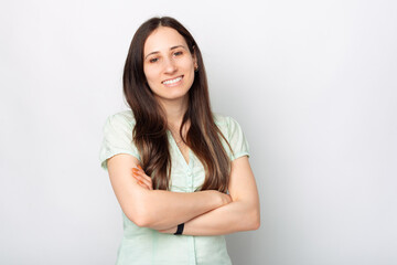 Fototapeta premium Portrait of young cheerful woman with crossed arms standing over white background