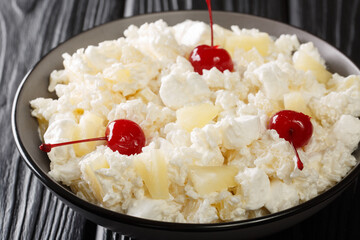 Sweet salad of rice, marshmallows and pineapple dressed with whipped cream close-up in a plate on the table. horizontal