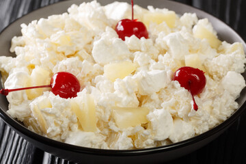 American dessert salad consisting of rice, marshmallows and pineapple dressed with whipped cream close-up in a plate on the table. horizontal