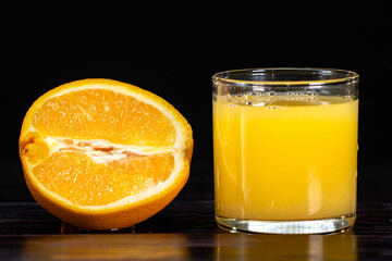 A ripe sliced orange and a glass of juice on a wooden background. close-up. healthy lifestyle. healthy eating. vitamins