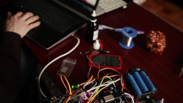 DIY, the machine on electronic control. Home experiments, robotics, smart engineer. Toy for the child. A man stitches an electronic device using a computer code of the program. laptop.