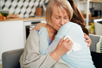 Woman hugging sad senior woman