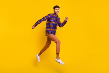 Fototapeta na wymiar Full length body size side profile photo of young man careless jumping running fast isolated vibrant yellow color background