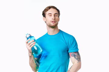 athlete in a blue t-shirt with a bottle of water on a white background and a tattoo on his arm