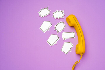 Yellow landline phone with speech bubble on purple background