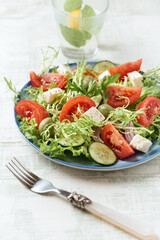Salad with Green Olives, Tomatoes and Feta Cheese. Bright wooden background. Close up.