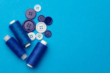 Thread spools and buttons on blue abckground