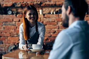 pretty woman waiter brings coffee service brick wall