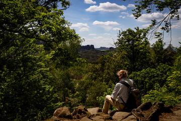 Ein Mann sitzt im Elbsandsteingebirge und genießt den Ausblick