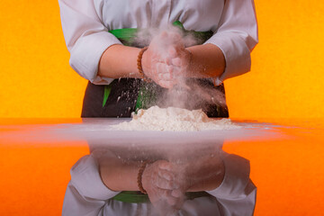 Female chef mixing flower on reflexive glass. 