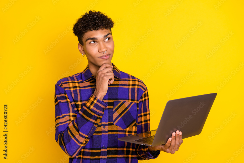 Wall mural Photo portrait of young man working on computer thinking looking empty space isolated vibrant yellow color background