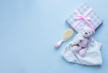 Greeting card for baby girl birth with teddy bear, present and baby hair brush on light grey background.