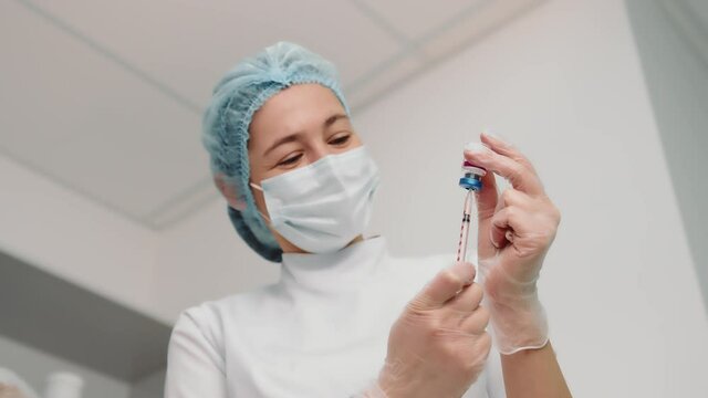 Nurse draws the vaccine into the syringe and prepares for the vaccination. A young nurse in a medical institution is vaccinated against coronavirus, influenza, and other diseases.