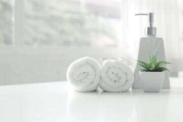 Fototapeta na wymiar Soap dispenser and spa towel ,Roll up of white towels on white table with copy space,towels studio shot on white table