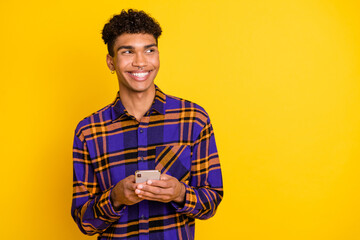 Photo portrait of man browsing internet mobile phone looking empty space wearing checkered outfit isolated on vivid yellow color background