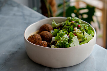 Vegan bowl with chickpea falafel balls and salad. Clean eating concept. Cruelty free fast food restaurant table with plate full of food. Close up, copy space, background.