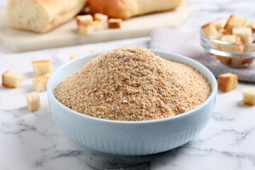 Fresh breadcrumbs in bowl on white marble table