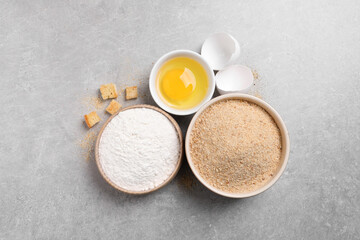 Fototapeta na wymiar Fresh breadcrumbs, flour and egg on light grey table, flat lay