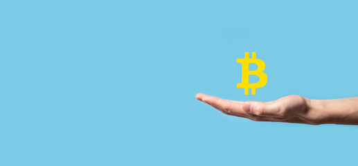 Male hand holding a bitcoin icon on blue background. Bitcoin Cryptocurrency Digital Bit Coin BTC Currency Technology Business Internet Concept.