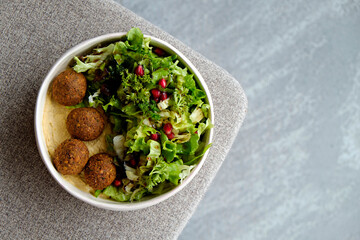 Vegan bowl with chickpea falafel balls and salad. Clean eating concept. Cruelty free fast food restaurant table with plate full of food. Close up, copy space, background.