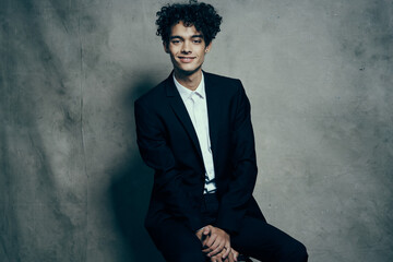 business man in a suit curly hair sitting on a chair fashion modern style