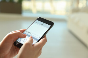 Woman writing message I Love You on smartphone against blurred background, closeup. Space for text
