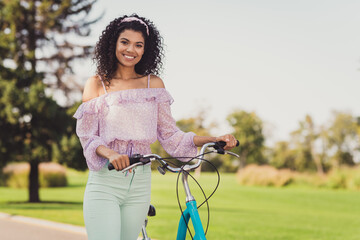 Photo of optimistic brunette lady stand with bicycle wear lilac top pants outside walk in park