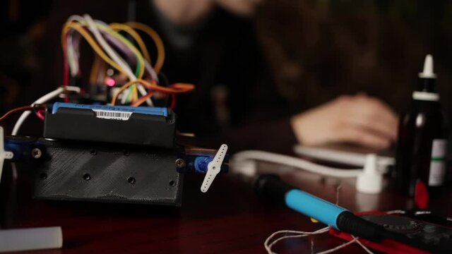 DIY, the machine on electronic control. Home experiments, robotics, smart engineer. Toy for the child. A man stitches an electronic device using a computer code of the program. laptop.