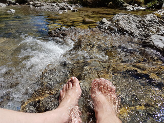closeup of womans feet, hardening in a cold mountain brook
