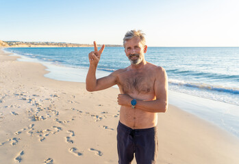 Mature happy active and healthy senior adult having fun on the beach enjoying retirement