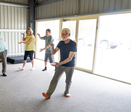 Group Of Elderly Senior People Practicing Tai Chi Class In Age Care Gym Facilities.