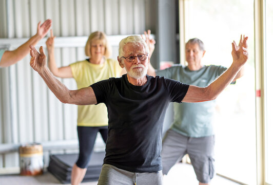 Group of elderly senior people practicing Tai chi class in age care gym facilities.