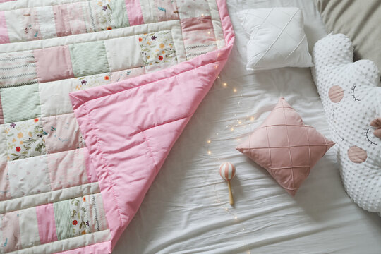Cozy baby cot with pink patchwork blanket. Baby bedding. Bedding and textile for nursery. Nap and sleep time