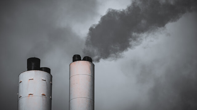 Smoke from an old ugly chimney set against a grey sky