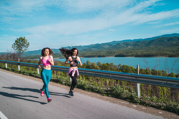 Sports young girls jogging near scenic lake. Active lifestyle girls workout