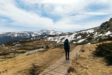 Woman hiker walking along the way to the snowy mountains. winter landscape