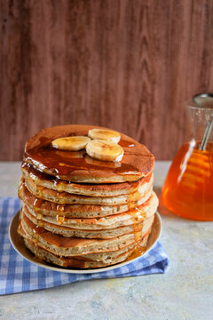 Pancakes with banana,walnut and muple syrup for a breakfast on wooden background closeup. Copy space. Vertical...