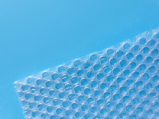 Bubble wrap packing or air cushion film on blue background. Closeup, copy space.